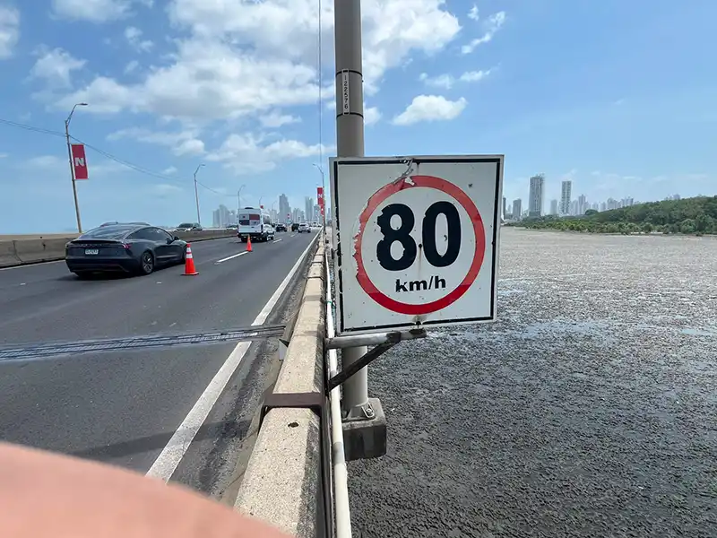 Señal de límite de velocidad de 80 km/h con desgaste visible instalada junto a una vía de alto tránsito