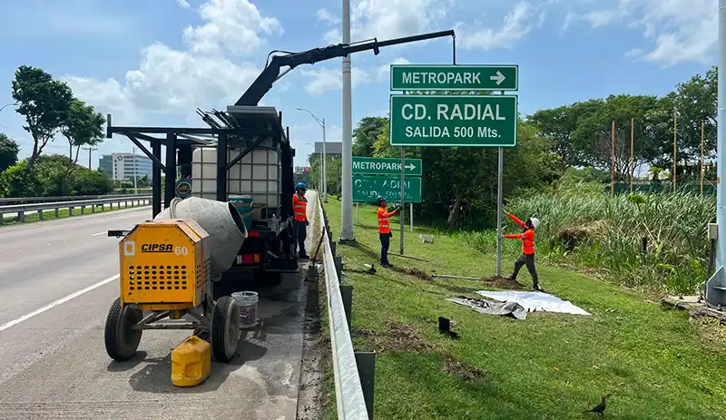 Técnicos instalando y dando mantenimiento a señalización vial direccional en una vía de alto tránsito